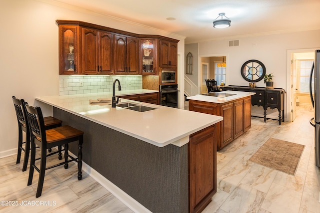 kitchen featuring a breakfast bar, sink, backsplash, oven, and kitchen peninsula