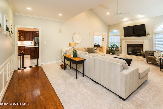 living room with crown molding, ceiling fan, high vaulted ceiling, and light hardwood / wood-style flooring