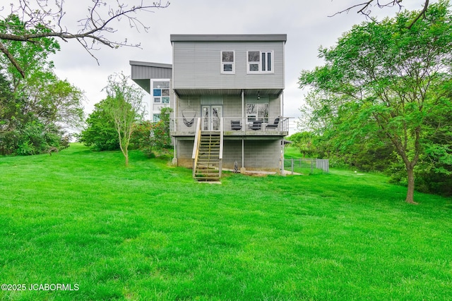 rear view of property with a lawn, a deck, and stairs