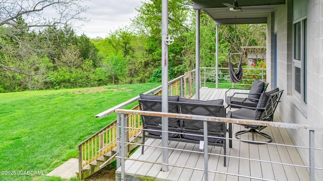 deck featuring a lawn, a wooded view, and ceiling fan