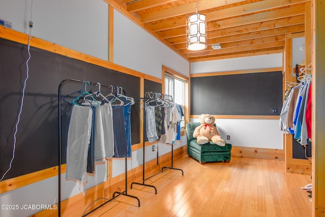 walk in closet with hardwood / wood-style floors and beamed ceiling