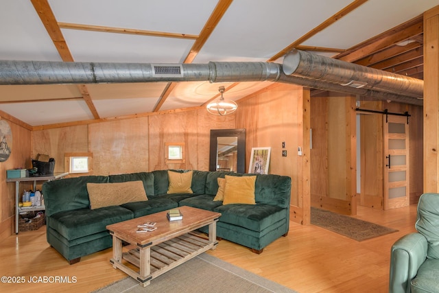 living area featuring a barn door, visible vents, wood finished floors, and wood walls