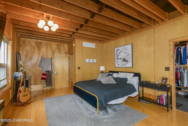 bedroom featuring a walk in closet, visible vents, wood finished floors, and a chandelier