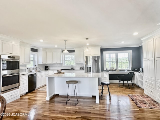 kitchen featuring tasteful backsplash, a breakfast bar area, appliances with stainless steel finishes, wood finished floors, and white cabinets