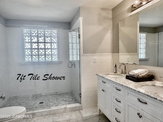 bathroom with a shower stall, toilet, double vanity, and a sink