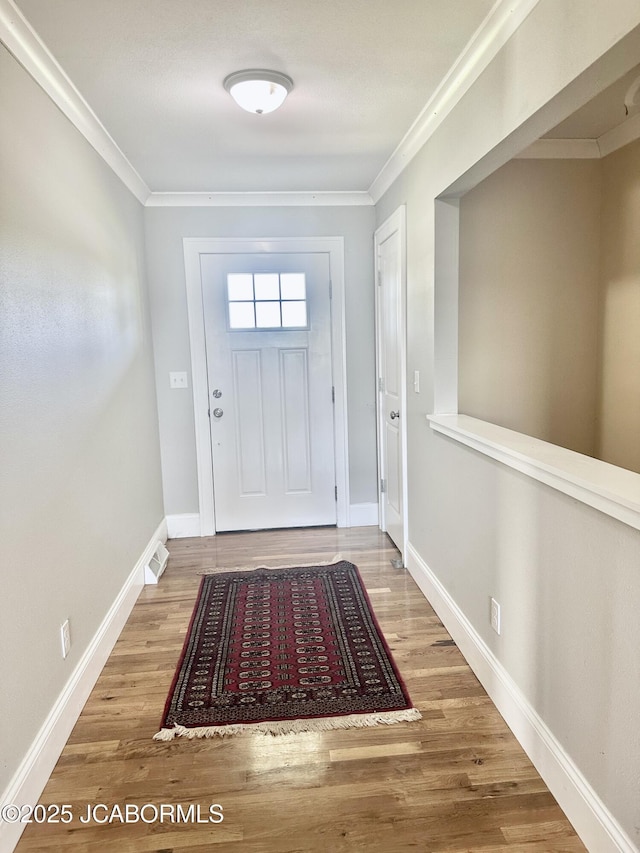 entryway with baseboards, wood finished floors, and crown molding