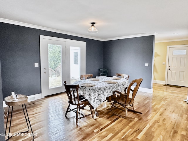 dining space with a wood stove, baseboards, light wood finished floors, and ornamental molding