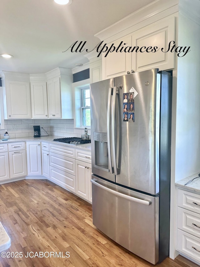 kitchen with decorative backsplash, light wood-style floors, appliances with stainless steel finishes, and white cabinets