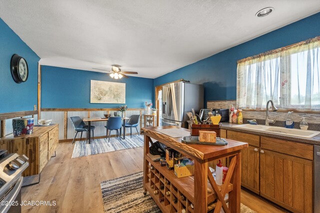 6733 Rocking Horse Ln, Fulton, MO 65251 - kitchen featuring appliances with stainless steel finishes, a sink, ceiling fan, light wood finished floors, and brown cabinetry