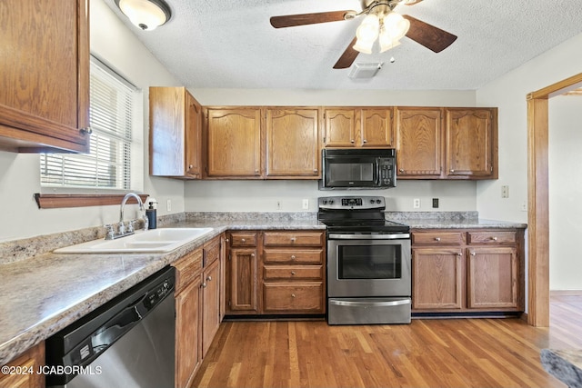 kitchen with sink, ceiling fan, a textured ceiling, light hardwood / wood-style floors, and stainless steel appliances