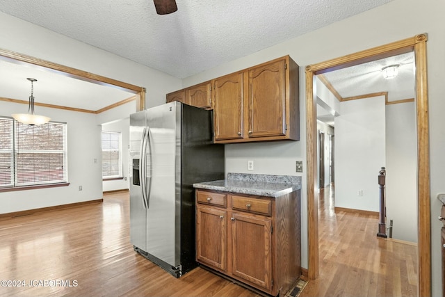 kitchen featuring decorative light fixtures, light hardwood / wood-style floors, stainless steel fridge with ice dispenser, and a textured ceiling