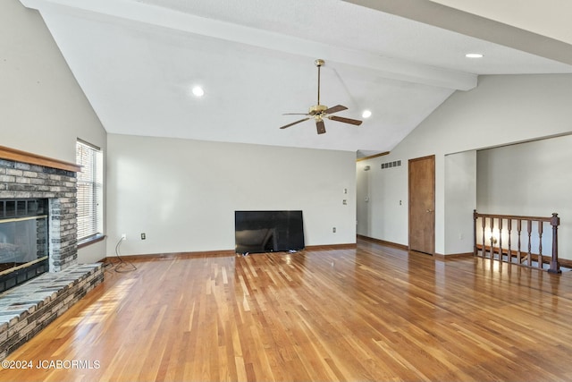 unfurnished living room featuring vaulted ceiling with beams, ceiling fan, hardwood / wood-style flooring, and a brick fireplace