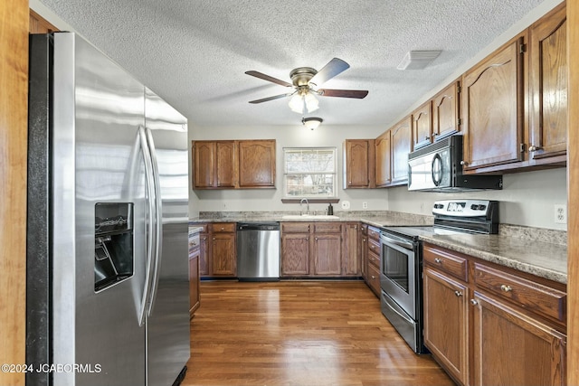 kitchen featuring ceiling fan, sink, dark wood-type flooring, a textured ceiling, and appliances with stainless steel finishes