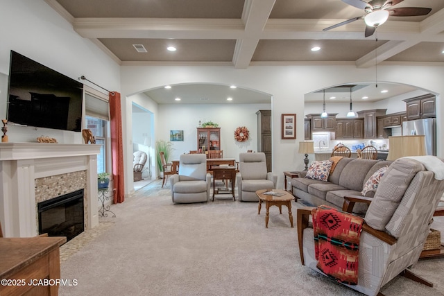 carpeted living room with coffered ceiling, crown molding, a tile fireplace, and beamed ceiling