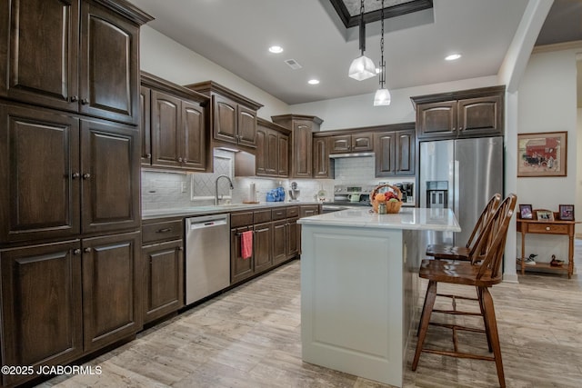 kitchen with stainless steel appliances, a center island, dark brown cabinets, and a breakfast bar area