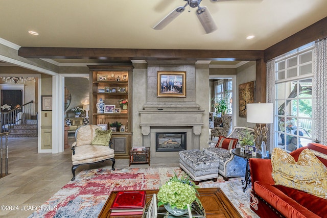 living room featuring ceiling fan, a large fireplace, and beamed ceiling