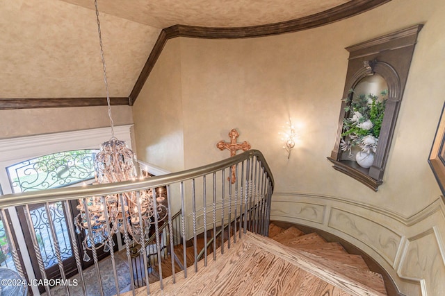 staircase with vaulted ceiling, hardwood / wood-style flooring, an inviting chandelier, and crown molding