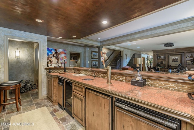 bar featuring ornate columns, sink, wine cooler, light stone counters, and crown molding