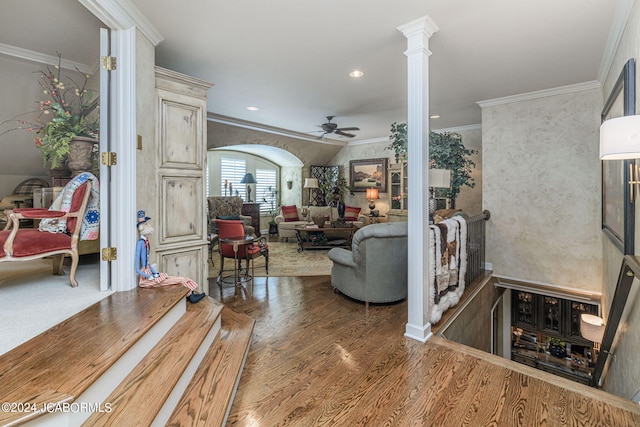 living room featuring dark wood-type flooring, ornate columns, ceiling fan, and crown molding