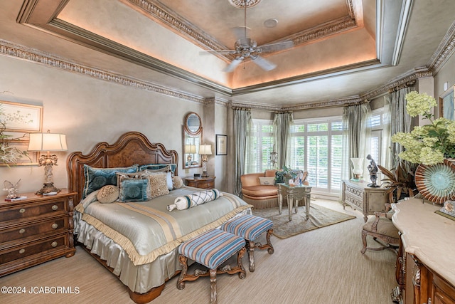 bedroom featuring a raised ceiling, crown molding, ceiling fan, and light colored carpet