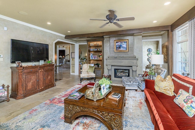 living room featuring a large fireplace, ceiling fan, and ornamental molding