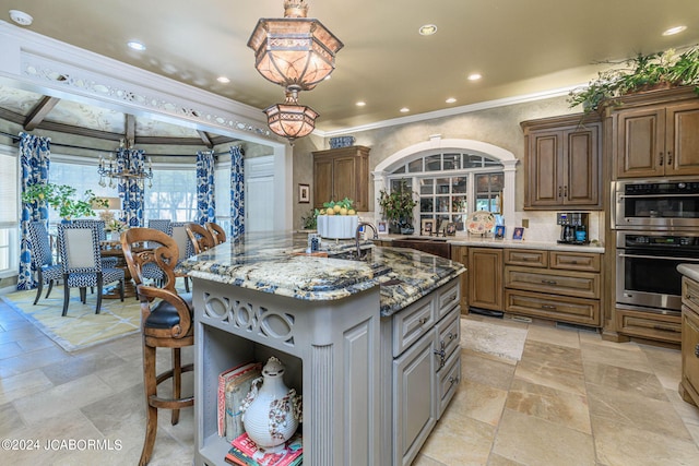 kitchen with a kitchen breakfast bar, a center island with sink, hanging light fixtures, and stone countertops