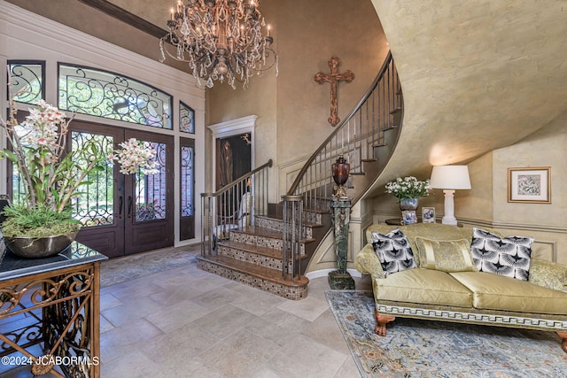 foyer entrance featuring french doors, a towering ceiling, and an inviting chandelier