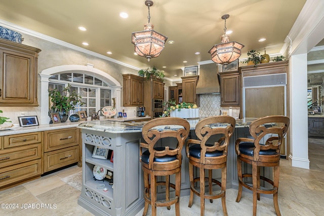 kitchen featuring decorative backsplash, a center island, pendant lighting, and custom range hood