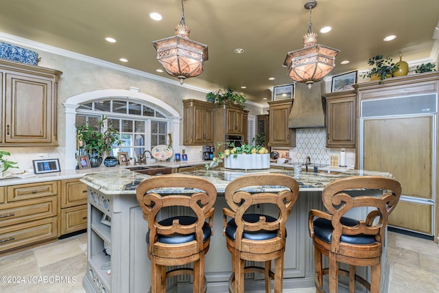 kitchen with paneled fridge, decorative light fixtures, a spacious island, and a kitchen bar