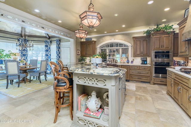 kitchen featuring double oven, light stone countertops, a center island, and hanging light fixtures