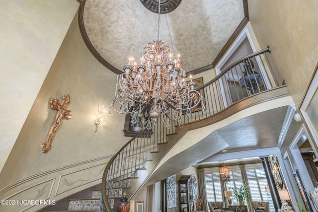 staircase with a chandelier, a high ceiling, and ornamental molding