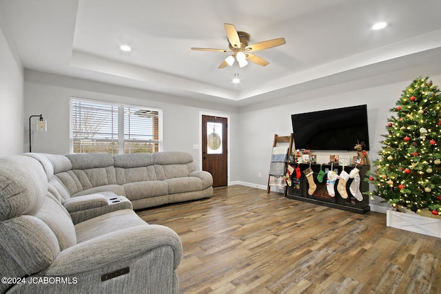 living room with ceiling fan, hardwood / wood-style floors, and a tray ceiling