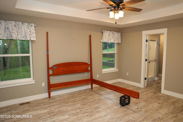 bedroom featuring baseboards, visible vents, multiple windows, and wood finished floors