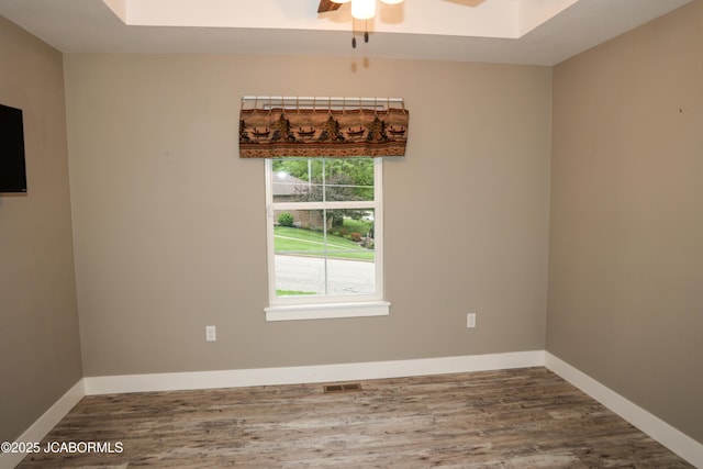 spare room featuring visible vents, baseboards, ceiling fan, and wood finished floors