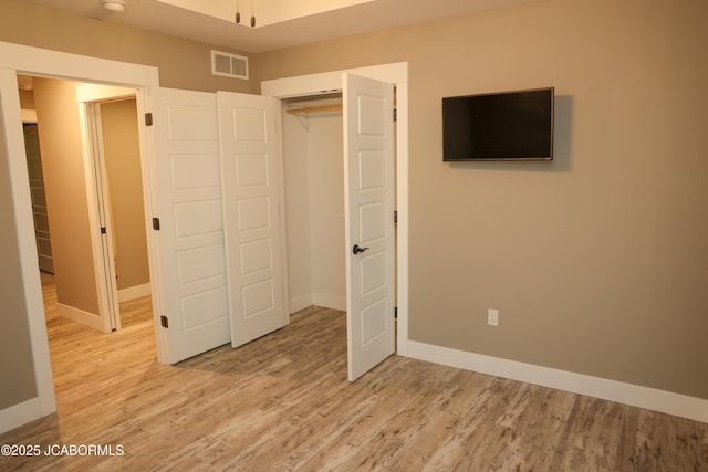 unfurnished bedroom with visible vents, light wood finished floors, and baseboards