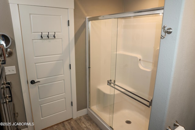 bathroom with a stall shower and wood finished floors