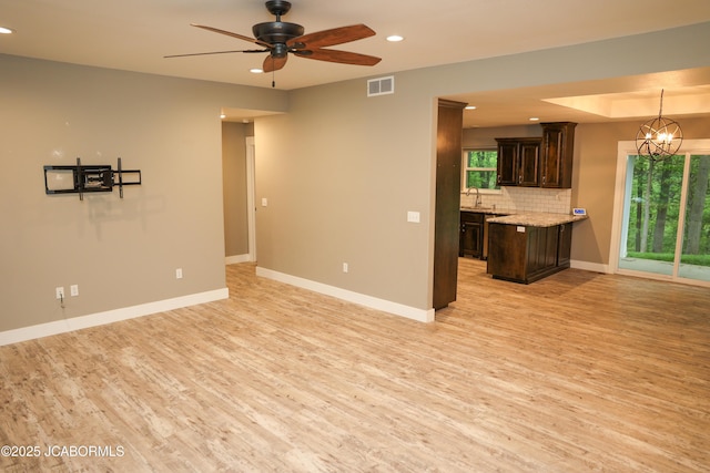 unfurnished living room with visible vents, a sink, ceiling fan with notable chandelier, recessed lighting, and light wood-style flooring