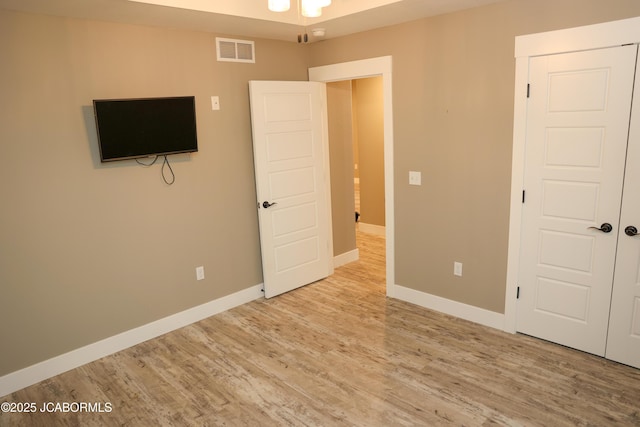 unfurnished bedroom featuring baseboards, visible vents, and wood finished floors