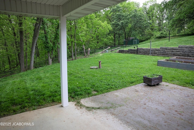 view of yard with an outdoor structure, fence, a shed, a vegetable garden, and a patio area