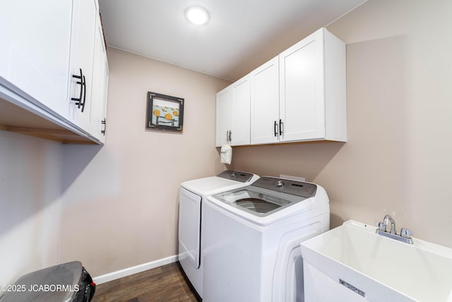 clothes washing area with dark wood-type flooring, independent washer and dryer, a sink, cabinet space, and baseboards