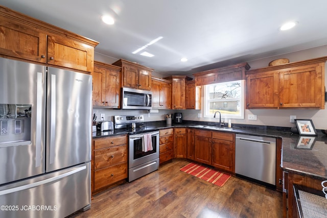 kitchen with brown cabinets, dark wood-style flooring, appliances with stainless steel finishes, and a sink