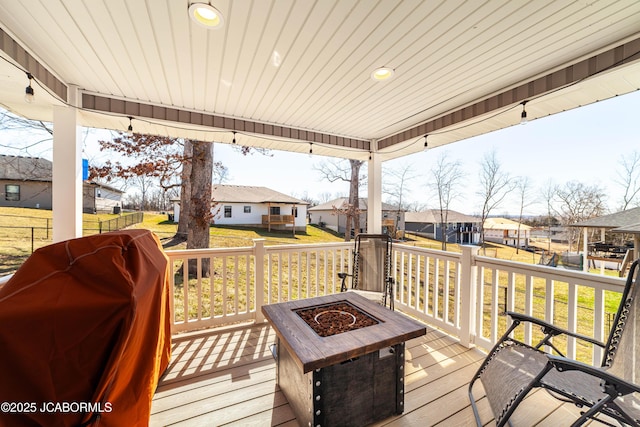 wooden terrace with an outdoor fire pit, a yard, a residential view, and a grill