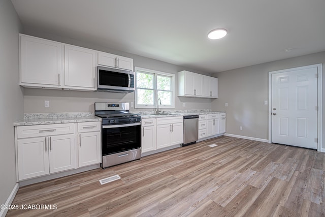 115 Middle St, Moberly, MO 65270 - kitchen with appliances with stainless steel finishes, light wood-type flooring, white cabinets, and baseboards
