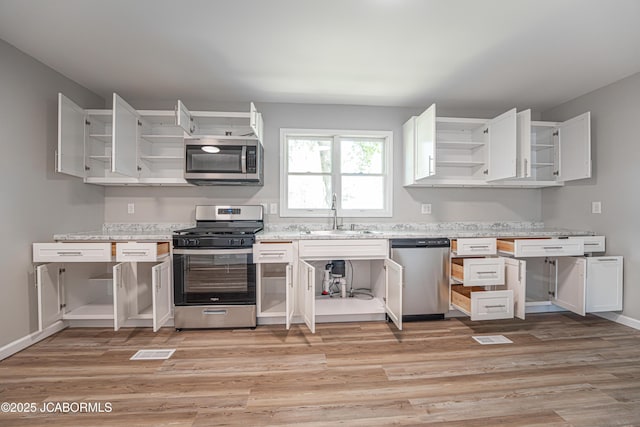 115 Middle St, Moberly, MO 65270 - kitchen with stainless steel appliances, open shelves, a sink, and light wood-style floors