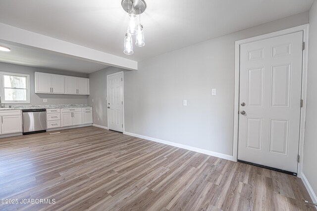 115 Middle St, Moberly, MO 65270 - kitchen with stainless steel dishwasher, light wood finished floors, white cabinets, and baseboards