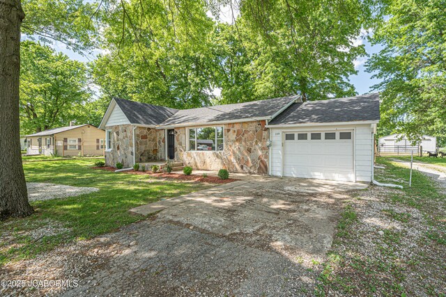 115 Middle St, Moberly, MO 65270 - view of front of home with concrete driveway, stone siding, a garage, and a front yard