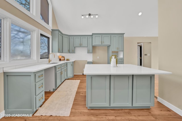 160 Ravenwood Dr, Camdenton, MO 65020 - kitchen with a sink, a center island, light wood-style floors, decorative backsplash, and baseboards