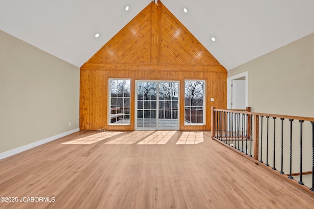 160 Ravenwood Dr, Camdenton, MO 65020 - empty room featuring wooden walls, wood finished floors, baseboards, and high vaulted ceiling