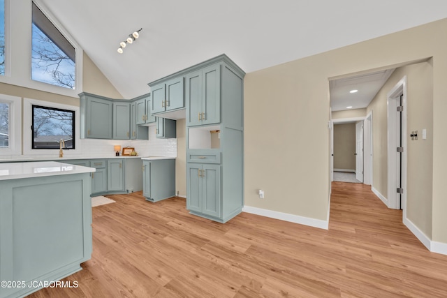 160 Ravenwood Dr, Camdenton, MO 65020 - kitchen with tasteful backsplash, baseboards, light countertops, light wood-style flooring, and high vaulted ceiling