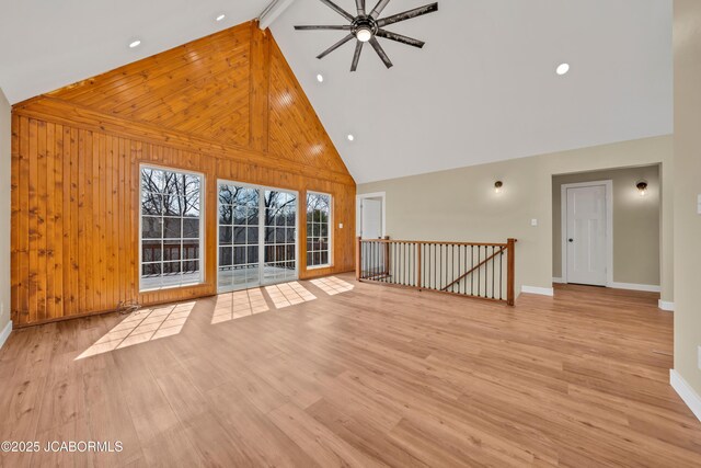 160 Ravenwood Dr, Camdenton, MO 65020 - unfurnished living room featuring a ceiling fan, wooden walls, wood finished floors, and high vaulted ceiling